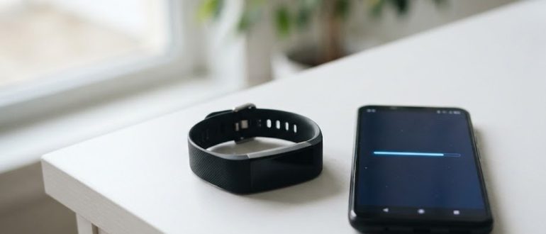 Фитнес-браслет рядом со смартфоном во время обновления прошивки
