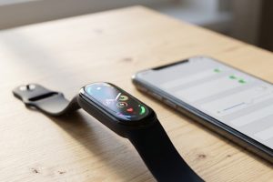 Фитнес-браслет с цветным экраном рядом со смартфоном на рабочем столе