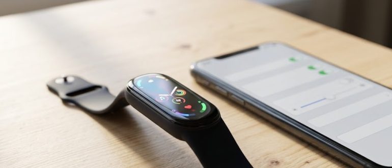 Фитнес-браслет с цветным экраном рядом со смартфоном на рабочем столе